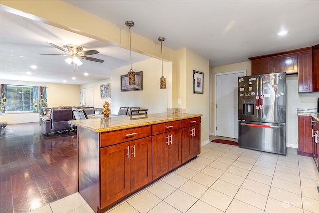 kitchen with stainless steel fridge with ice dispenser, light stone counters, kitchen peninsula, pendant lighting, and light wood-type flooring