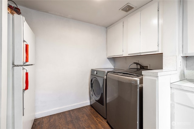 washroom with cabinets, dark hardwood / wood-style flooring, and washing machine and clothes dryer