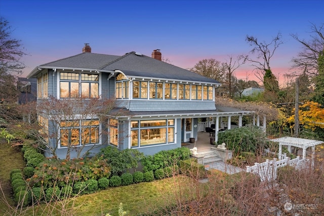 back house at dusk featuring covered porch