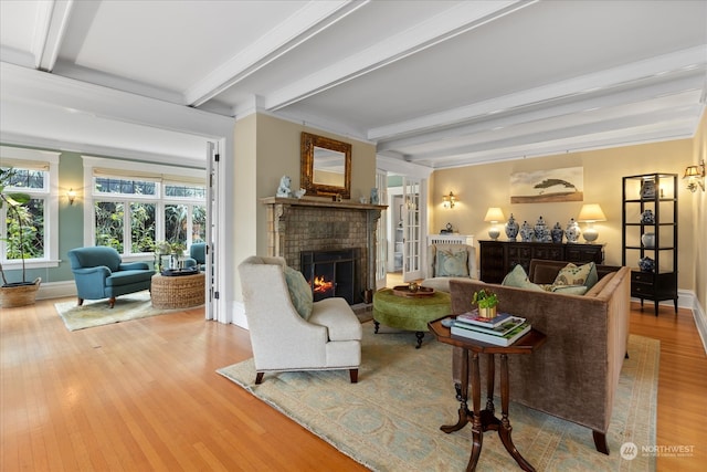 living room featuring a brick fireplace, crown molding, beamed ceiling, and light wood-type flooring