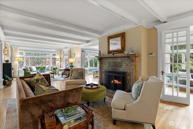 living room featuring a tile fireplace, beamed ceiling, and hardwood / wood-style flooring