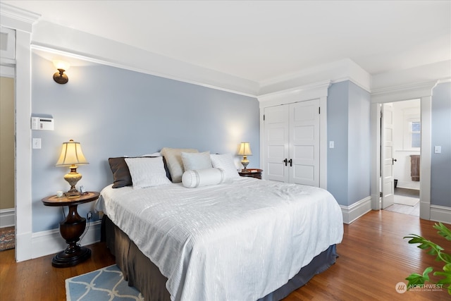 bedroom with hardwood / wood-style floors, ornamental molding, connected bathroom, and a closet