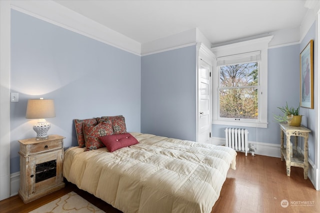 bedroom featuring wood-type flooring, radiator, and crown molding