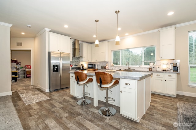 kitchen with a center island, white cabinets, stainless steel appliances, and wall chimney range hood