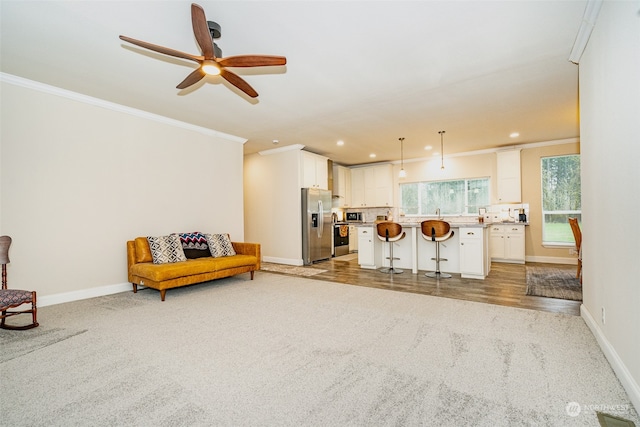 living room featuring ceiling fan, ornamental molding, and light wood-type flooring