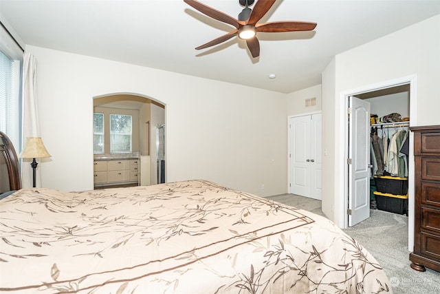 carpeted bedroom featuring ceiling fan, a closet, a spacious closet, and multiple windows