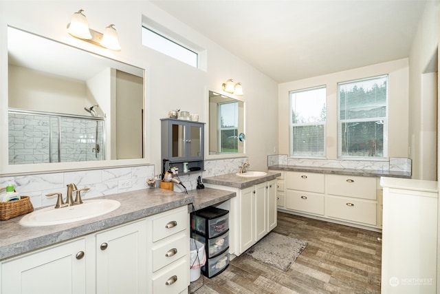 bathroom with a shower with shower door, wood-type flooring, backsplash, and vanity