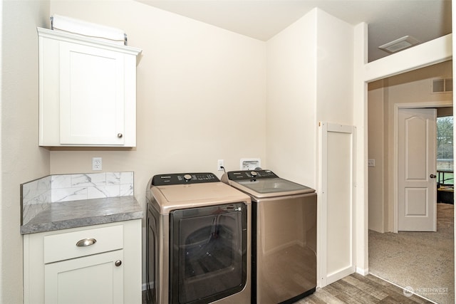 laundry area with cabinets, separate washer and dryer, and dark wood-type flooring