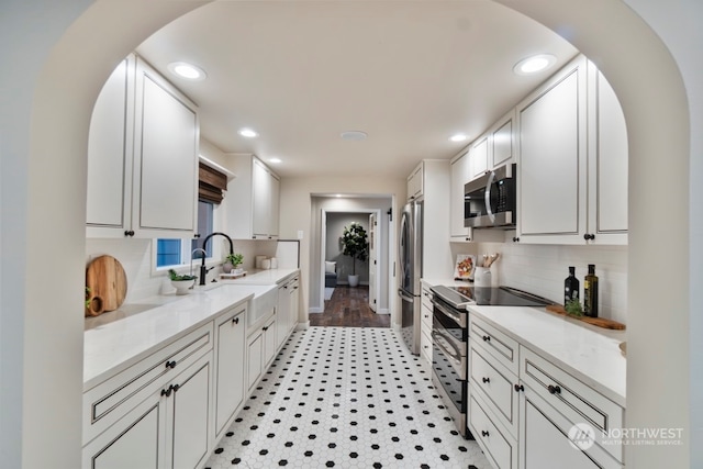 kitchen featuring sink, light stone countertops, light wood-type flooring, white cabinetry, and stainless steel appliances