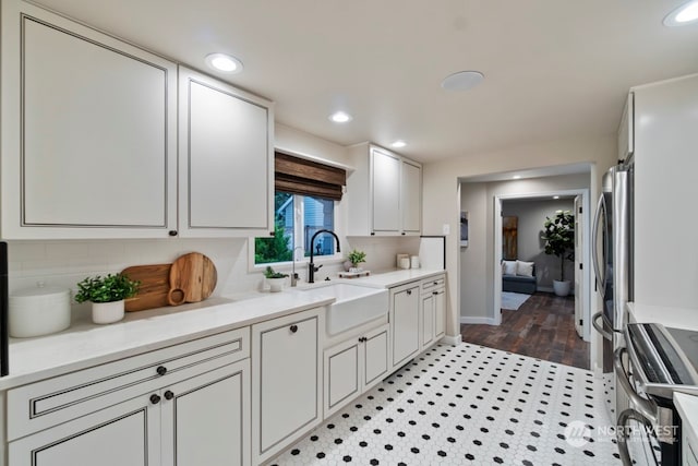 kitchen with light hardwood / wood-style floors, sink, stainless steel range, and tasteful backsplash