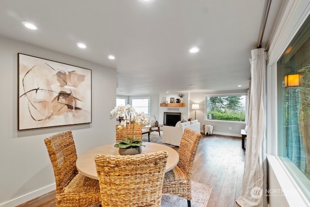 dining space with a healthy amount of sunlight, light wood-type flooring, and a fireplace