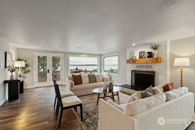 living room with dark hardwood / wood-style flooring, a brick fireplace, and a healthy amount of sunlight