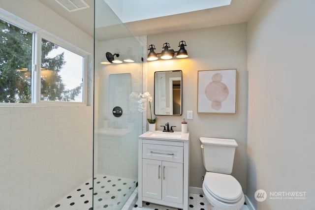 bathroom with tile patterned floors, vanity, toilet, and tiled shower