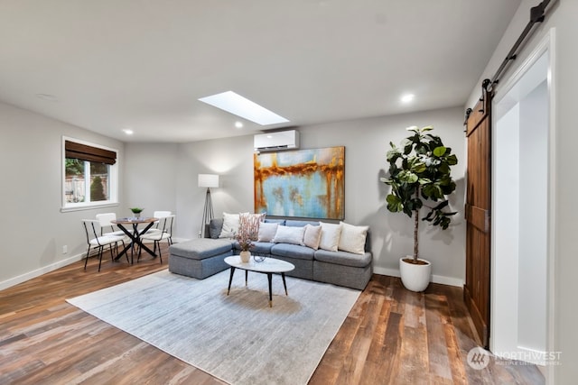 living room featuring a wall mounted air conditioner, a barn door, wood-type flooring, and a skylight