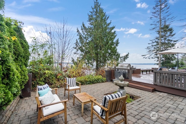 view of patio / terrace with a deck with water view, outdoor lounge area, and a grill