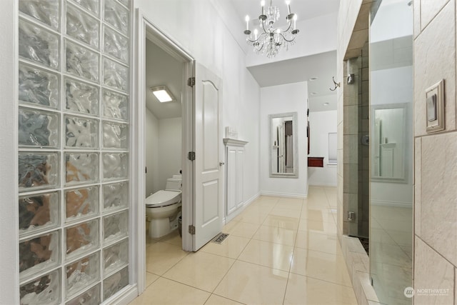 bathroom featuring tile patterned floors, a notable chandelier, toilet, and a shower with door