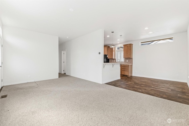 unfurnished living room featuring sink and dark wood-type flooring