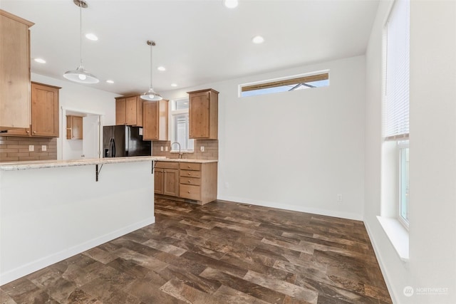 kitchen with a breakfast bar area, black refrigerator with ice dispenser, hanging light fixtures, and a healthy amount of sunlight