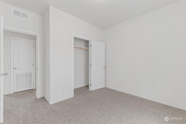 unfurnished bedroom featuring light colored carpet and a closet