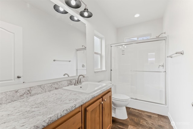 bathroom featuring hardwood / wood-style floors, vanity, toilet, and a shower with door