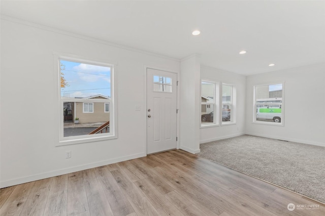 foyer entrance featuring light hardwood / wood-style floors, plenty of natural light, and ornamental molding