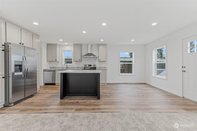 kitchen featuring a healthy amount of sunlight, light wood-type flooring, stainless steel appliances, and wall chimney exhaust hood