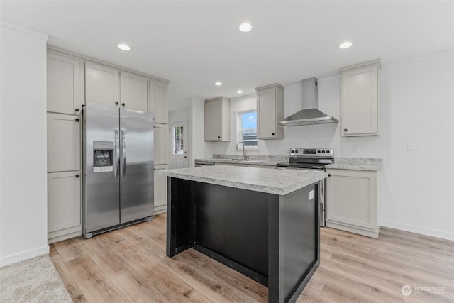 kitchen featuring a center island, light hardwood / wood-style floors, wall chimney range hood, and appliances with stainless steel finishes