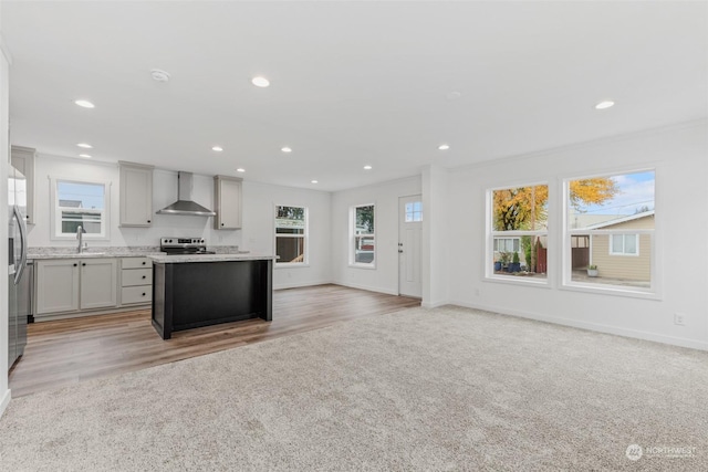 kitchen featuring a wealth of natural light, gray cabinetry, and wall chimney range hood