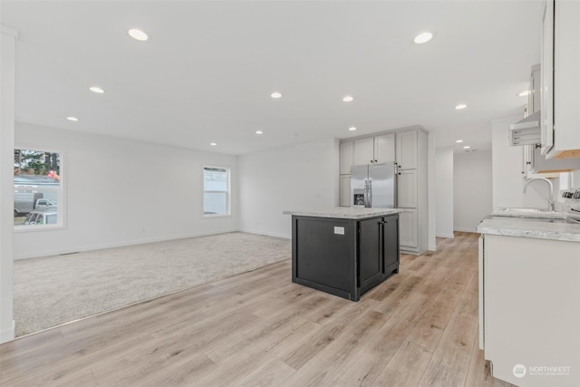 kitchen with stainless steel refrigerator with ice dispenser, sink, light hardwood / wood-style flooring, white cabinets, and a center island