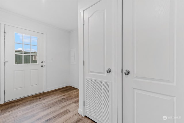 doorway with light hardwood / wood-style floors and crown molding