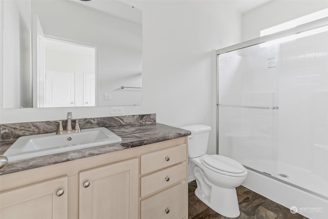 bathroom featuring vanity, toilet, and a shower with door