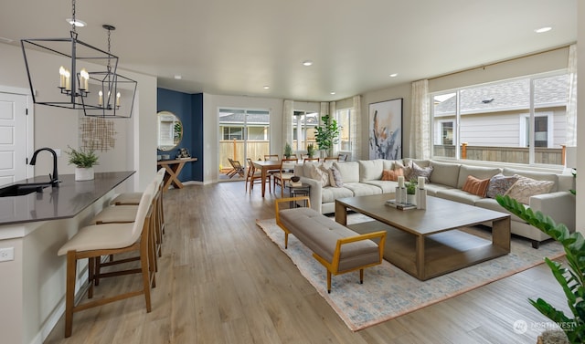 living room with a chandelier, light hardwood / wood-style flooring, a wealth of natural light, and sink