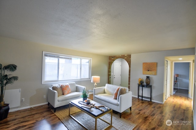 living room with a textured ceiling and dark hardwood / wood-style floors