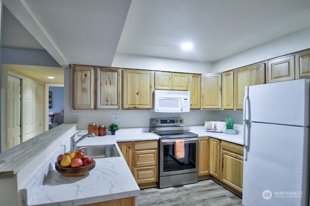 kitchen with sink, white appliances, kitchen peninsula, and light wood-type flooring