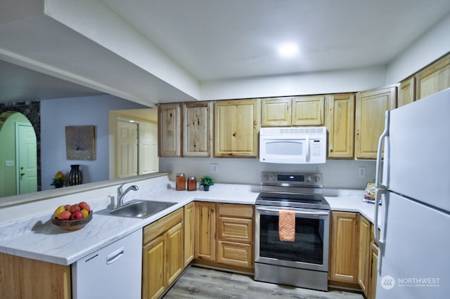 kitchen with sink, white appliances, kitchen peninsula, and light wood-type flooring