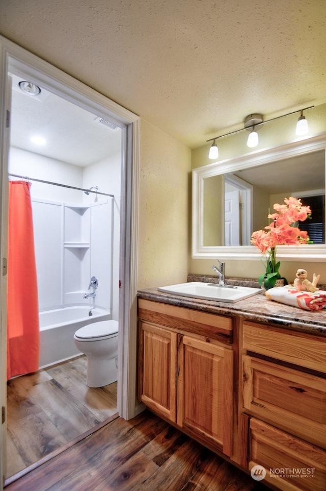 full bathroom featuring hardwood / wood-style flooring, vanity, toilet, and shower / tub combo