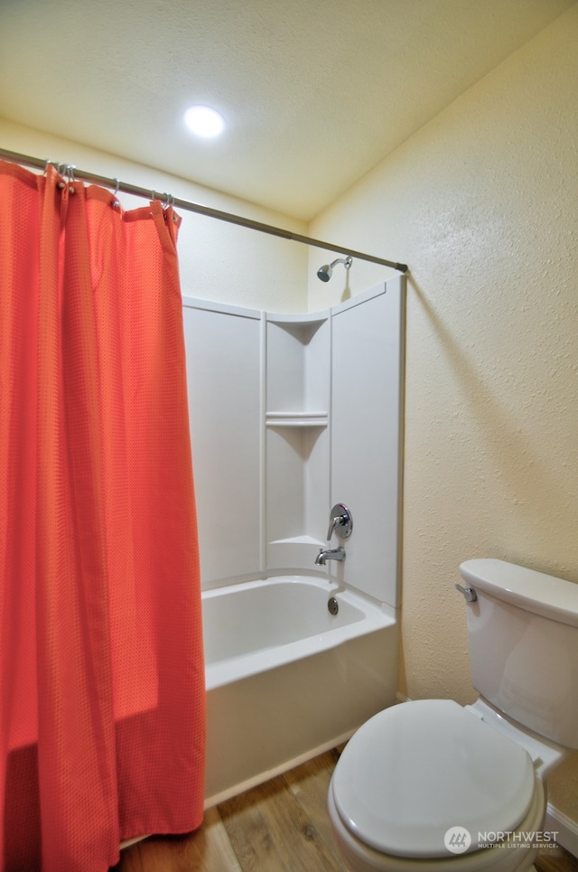 bathroom featuring hardwood / wood-style flooring, toilet, and shower / bathtub combination with curtain