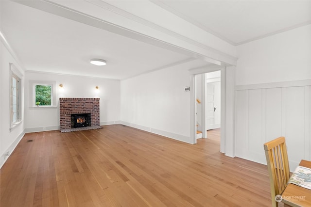 unfurnished living room featuring a brick fireplace, crown molding, and light wood-type flooring