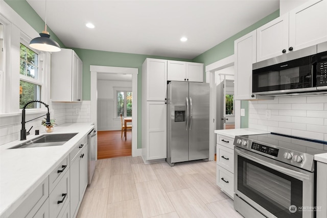 kitchen with white cabinets, appliances with stainless steel finishes, plenty of natural light, and sink