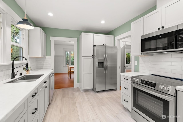 3608 Gay Rd E, Tacoma, WA 98443 - kitchen featuring stainless steel appliances, a sink, light countertops, white cabinets, and decorative backsplash