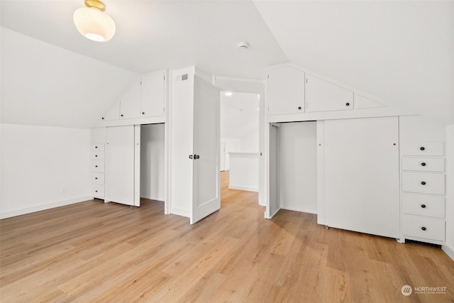 additional living space with light hardwood / wood-style floors and lofted ceiling