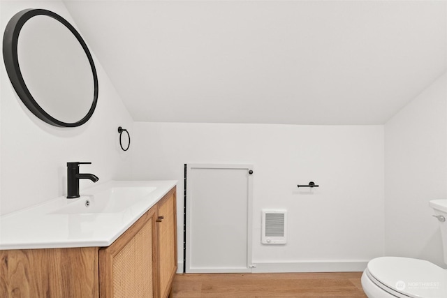 bathroom featuring hardwood / wood-style floors, vanity, lofted ceiling, and toilet