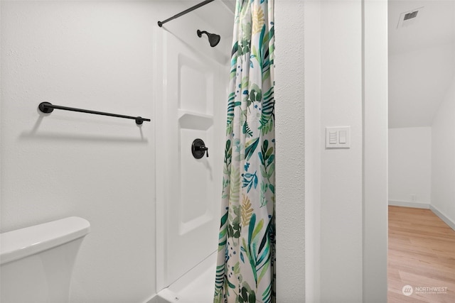 bathroom featuring hardwood / wood-style flooring, toilet, and walk in shower