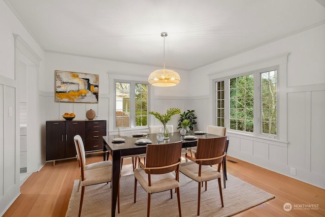 dining room with ornamental molding, a wealth of natural light, and light hardwood / wood-style flooring