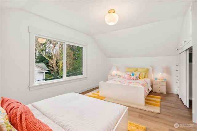 bedroom featuring light hardwood / wood-style floors and lofted ceiling