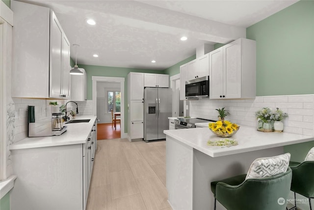 kitchen featuring white cabinetry, a breakfast bar, decorative light fixtures, and appliances with stainless steel finishes