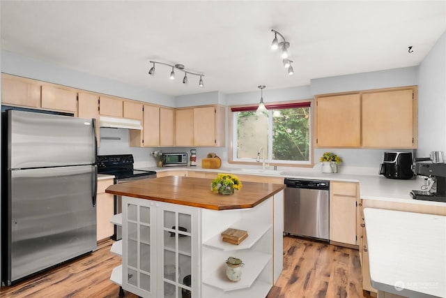 kitchen with sink, light wood-type flooring, light brown cabinetry, appliances with stainless steel finishes, and decorative light fixtures