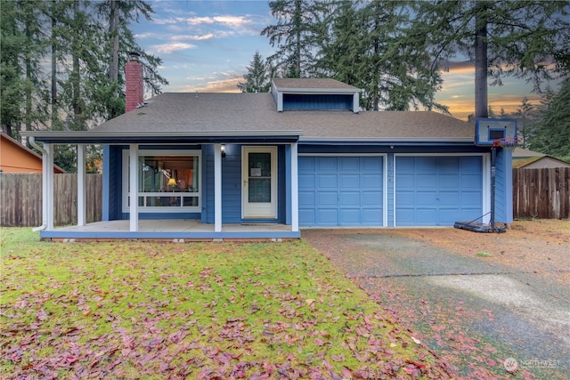 view of front facade featuring covered porch, a yard, and a garage