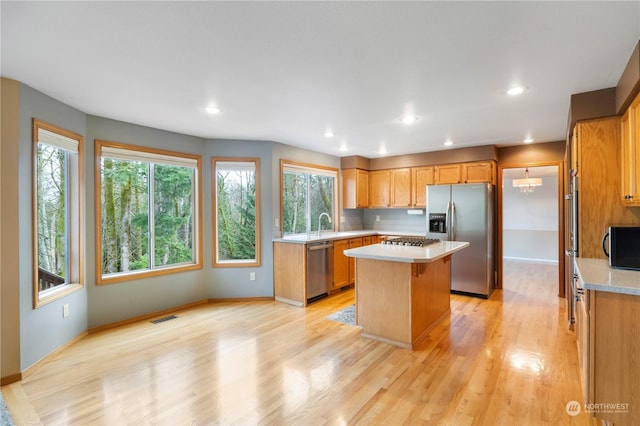 kitchen with appliances with stainless steel finishes, a center island, light hardwood / wood-style floors, and a healthy amount of sunlight