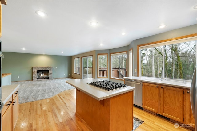 kitchen featuring a center island, sink, a brick fireplace, light hardwood / wood-style floors, and stainless steel appliances